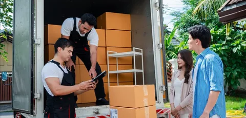 Movers checking a delivery list with customers beside a moving truck.