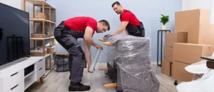 Professional movers wrapping furniture with protective plastic
