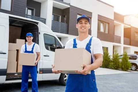 Moving company workers delivering boxes in front of a modern residential building